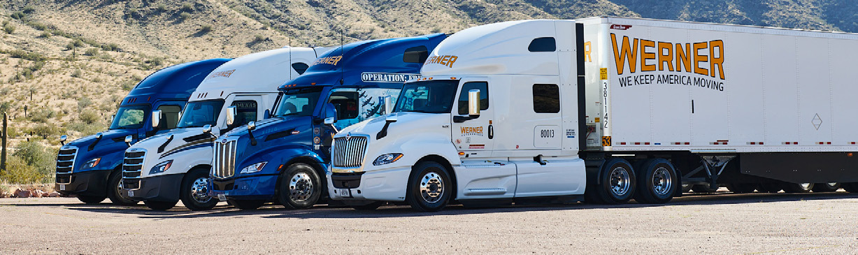 A row of Werner trucks and trailers parked in the desert