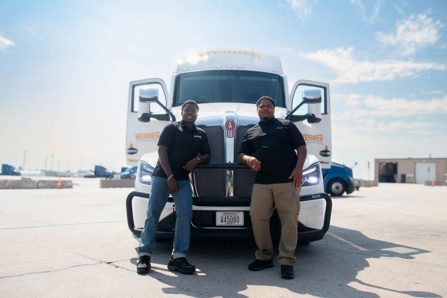 Two Werner Enterprises team drivers posing in front of their semi-truck.