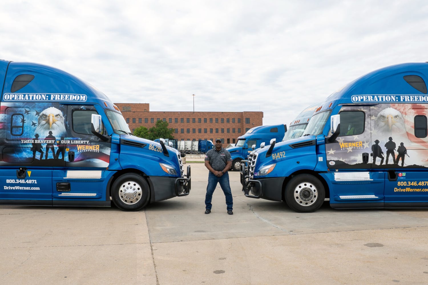 Werner veteran driver standing between two Operation Freedom trucks